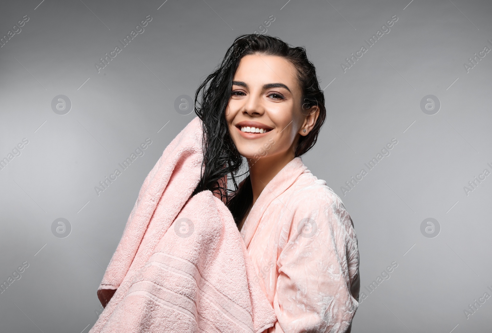 Photo of Happy young woman drying hair with towel after washing on light grey background