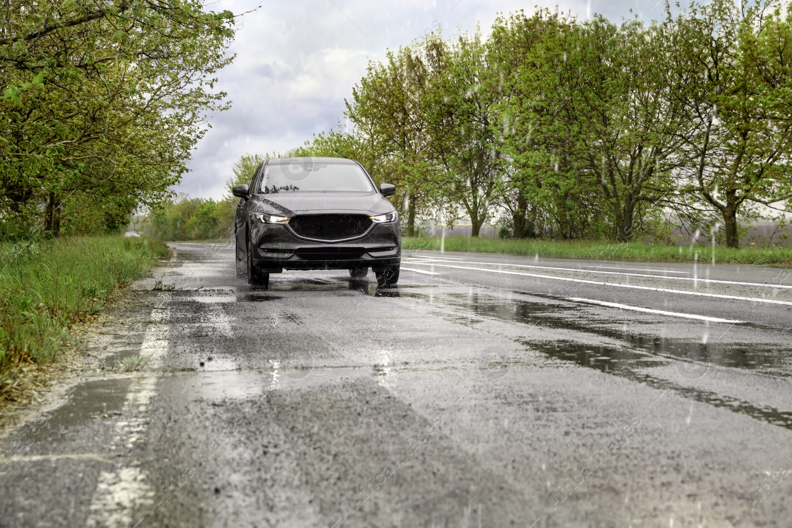 Photo of Wet suburban road with car on rainy day