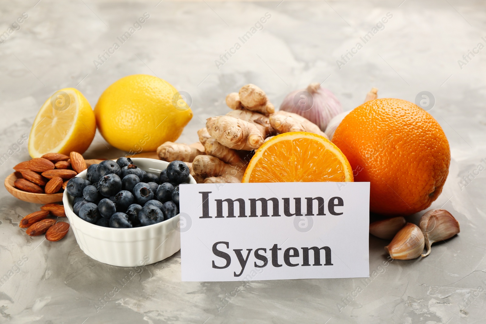 Photo of Card with phrase Immune System and fresh products on light marble background