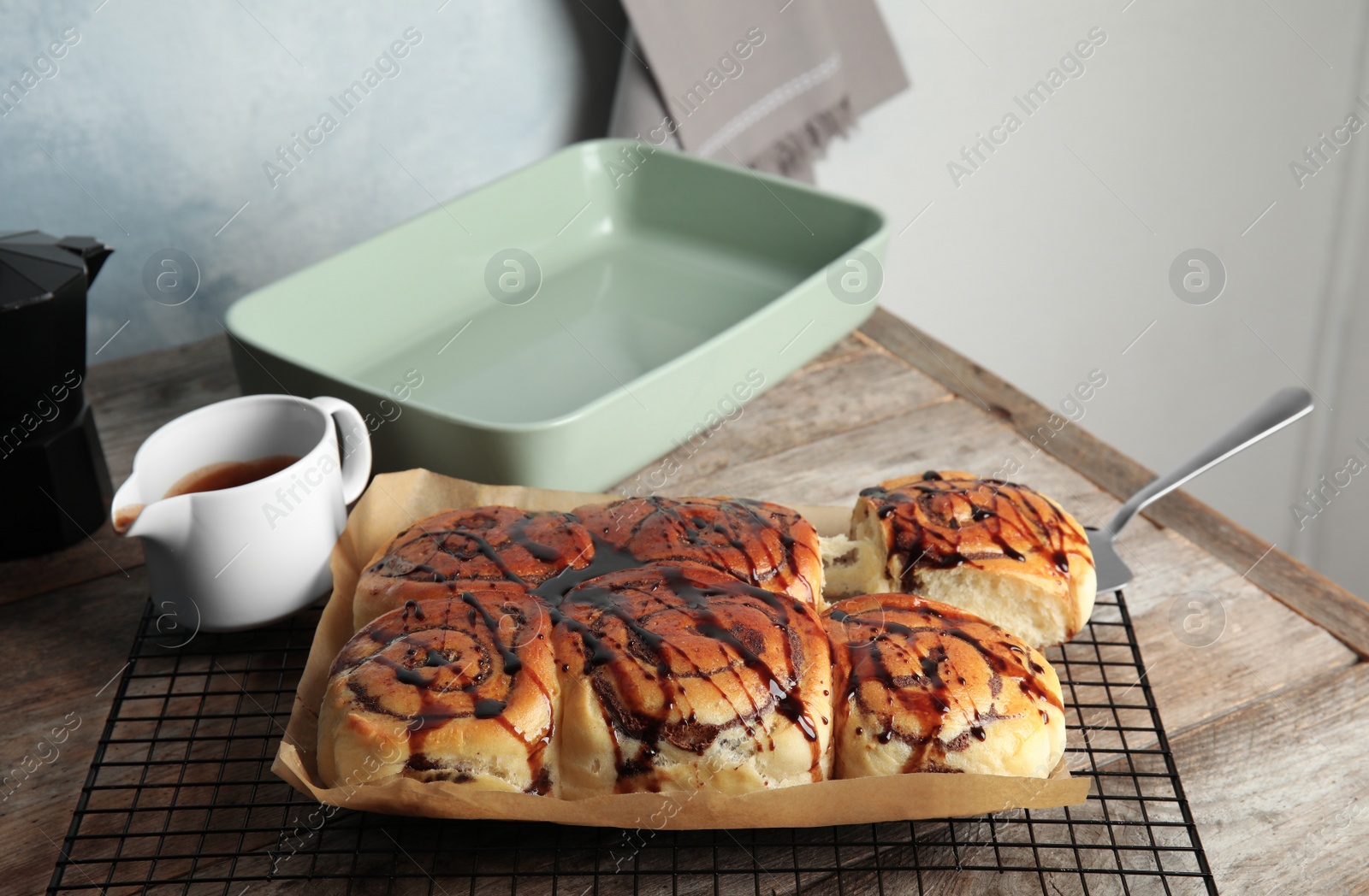 Photo of Cooling rack with freshly baked cinnamon rolls on table