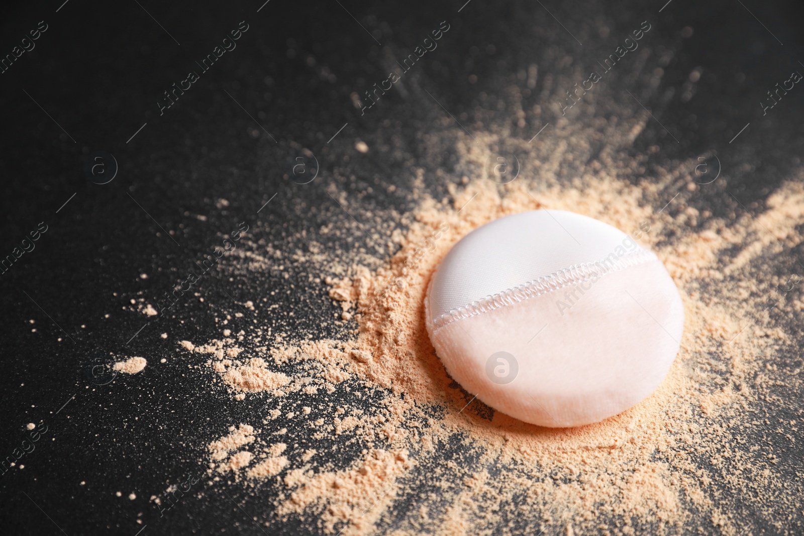 Photo of Puff applicator and loose face powder on black background, closeup