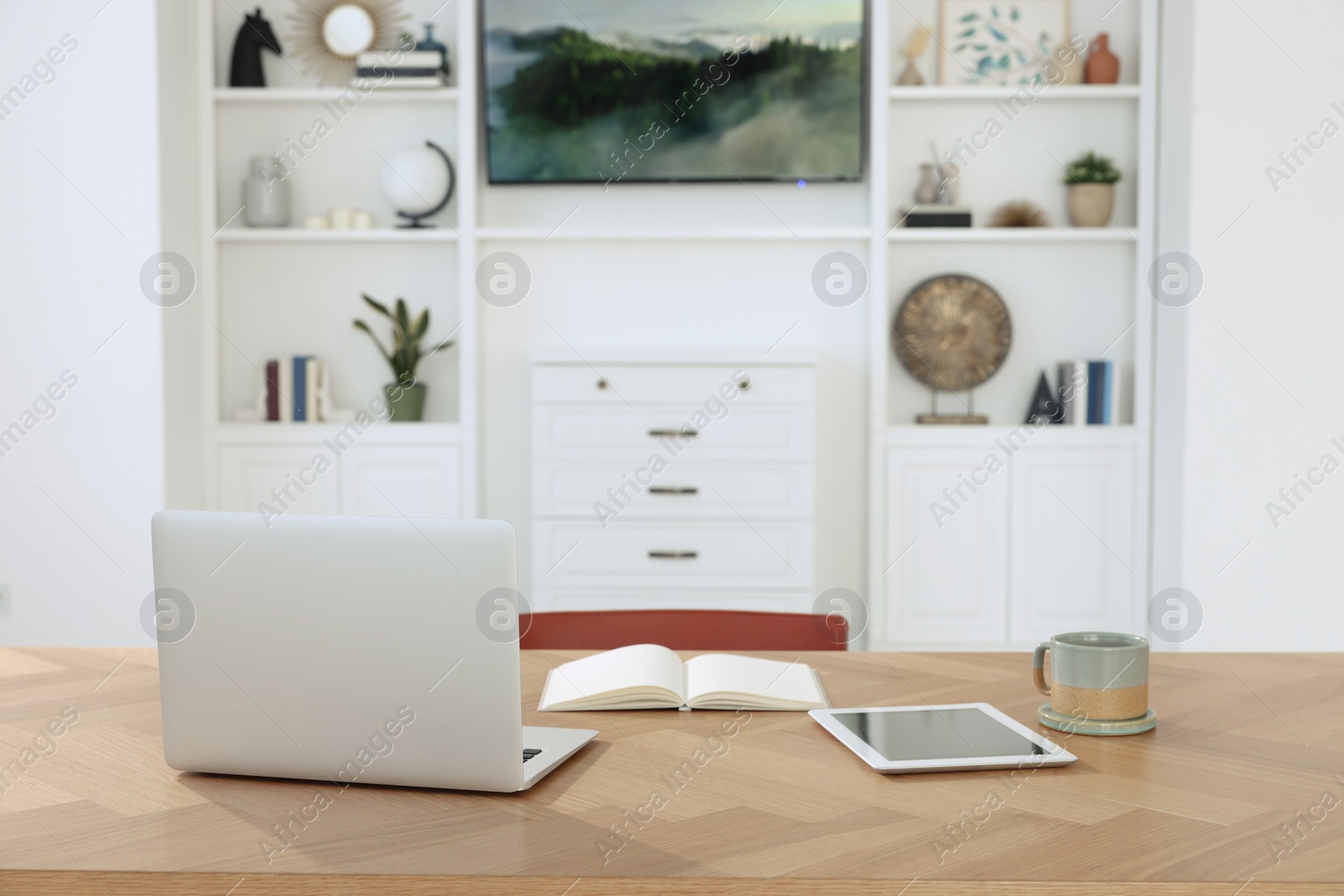 Photo of Interior design. Cosy workplace with laptop and tablet near tv area