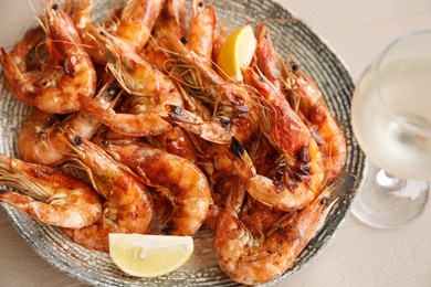 Photo of Plate of delicious cooked shrimps served with lemon and wine at table, closeup