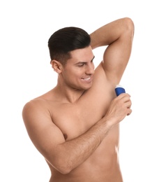 Handsome man applying deodorant to armpit on white background