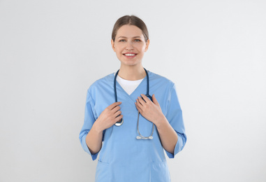 Photo of Young doctor with stethoscope against light background