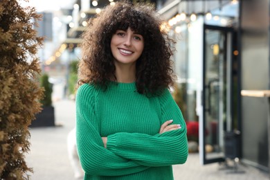 Photo of Happy young woman in stylish green sweater outdoors