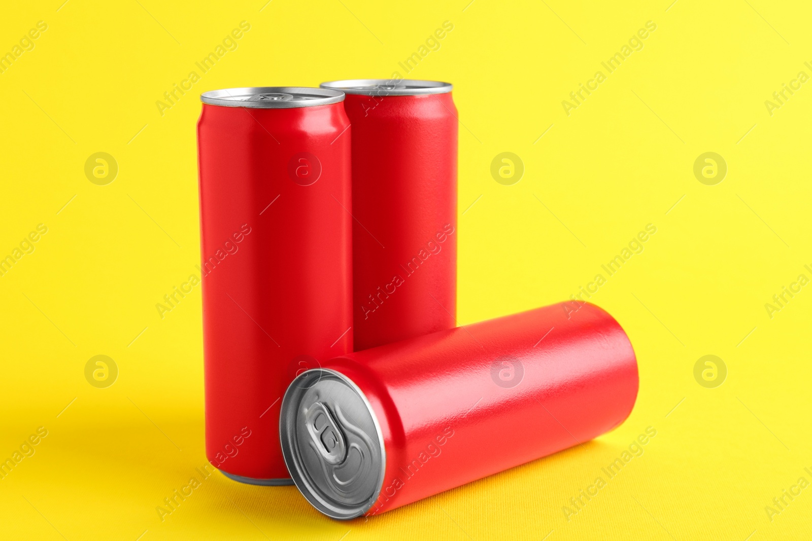 Photo of Energy drinks in red cans on yellow background