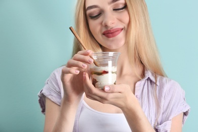 Young woman with yogurt on color background, closeup