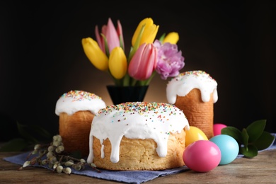 Photo of Easter cakes and painted eggs on wooden table