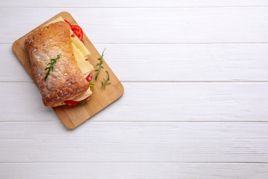 Photo of Delicious sandwich with cheese, salami, tomato on white wooden table, top view. Space for text