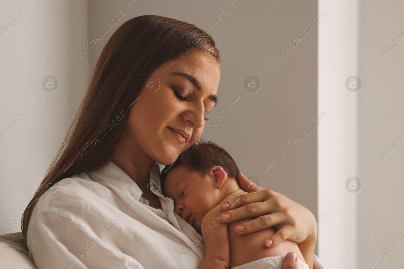 Photo of Mother holding her cute newborn baby indoors