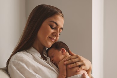 Mother holding her cute newborn baby indoors