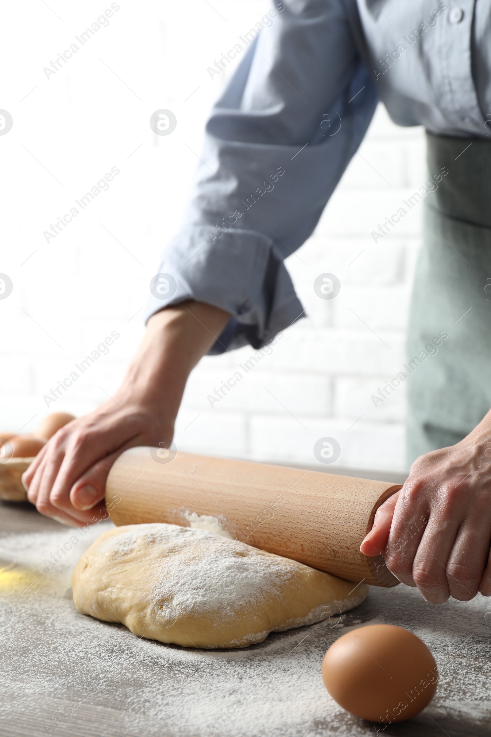 Photo of Woman rolling raw dough at table, closeup