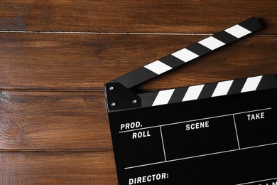 Clapperboard on wooden table, top view. Space for text