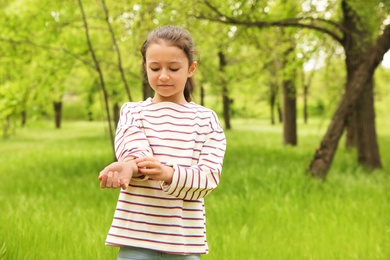 Photo of Little girl scratching hand outdoors, space for text. Seasonal allergy