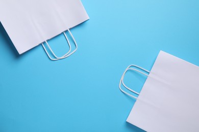 Photo of White paper bags on light blue background, top view. Space for text