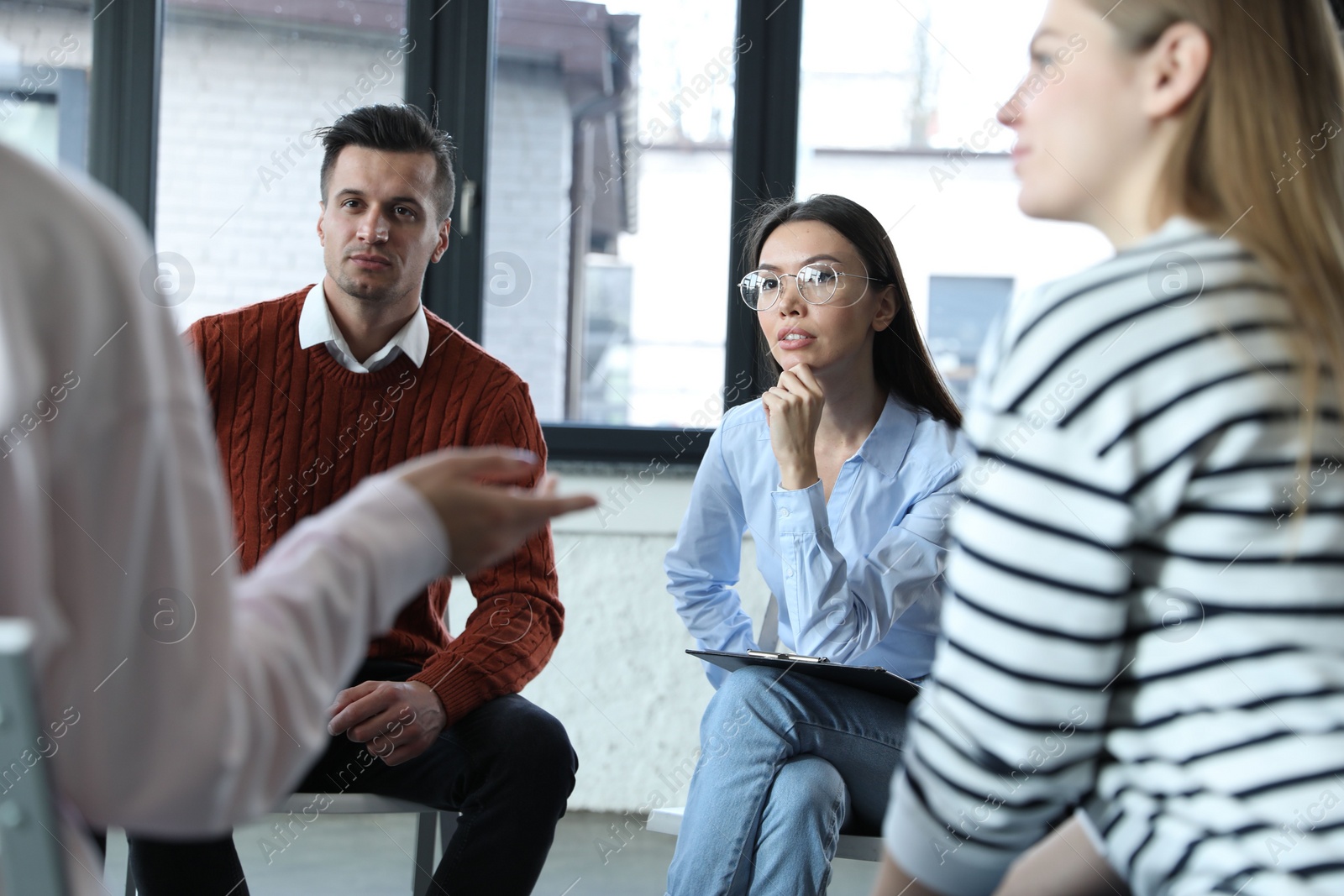 Photo of Psychotherapist working with patients in group therapy session indoors