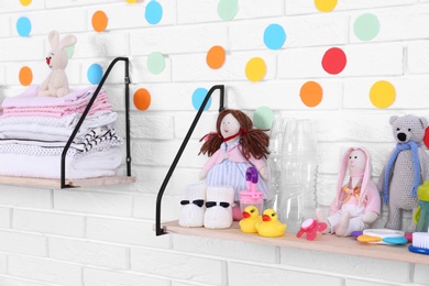 Baby accessories on shelves near white brick wall