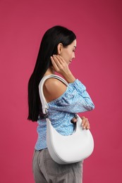 Fashionable young woman with stylish bag on pink background