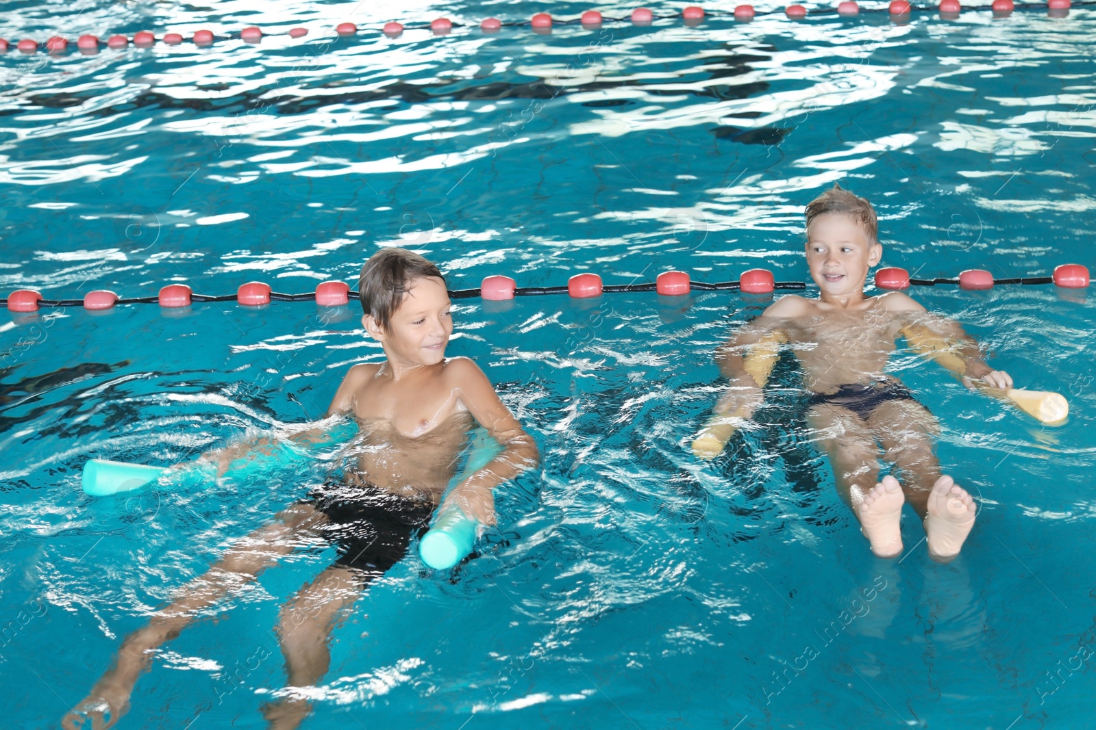 Photo of Little boys with swimming noodles in indoor pool