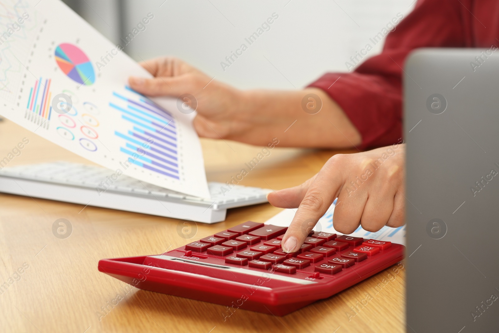 Photo of Accountant using calculator at wooden desk in office, closeup