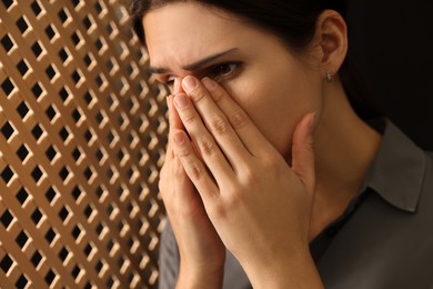 Photo of Upset woman covering face with hands and listening to priest during confession in booth, closeup