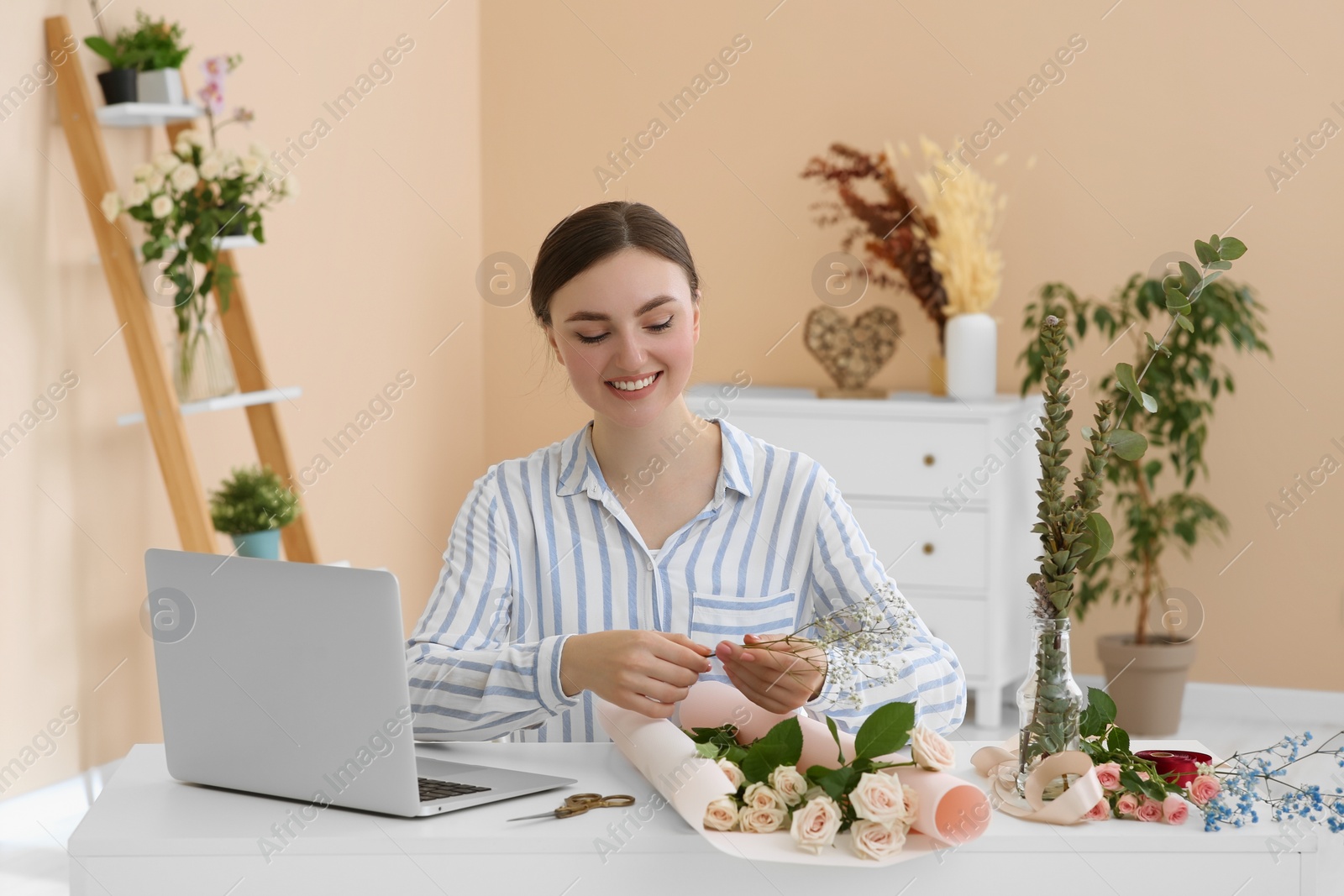 Photo of Woman making bouquet following online florist course at home. Time for hobby