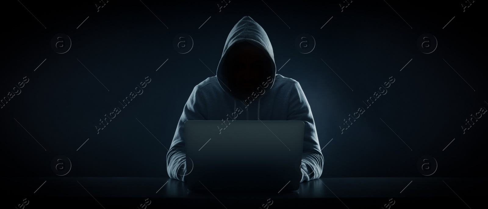 Image of Anonymous man in hood using laptop on black background. Banner design