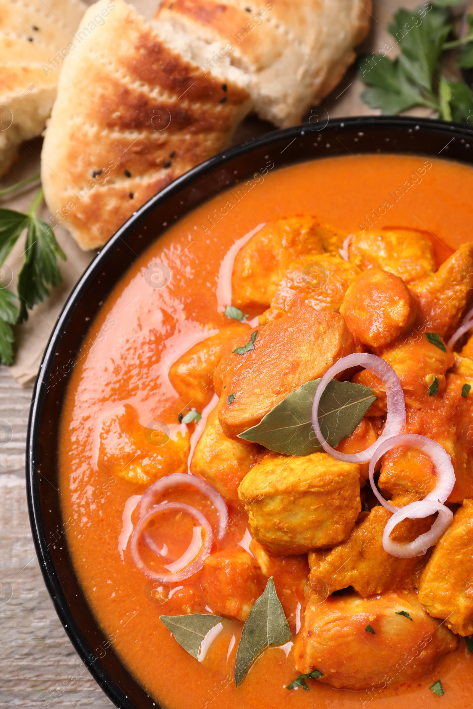 Photo of Delicious chicken curry in pan on wooden table, flat lay