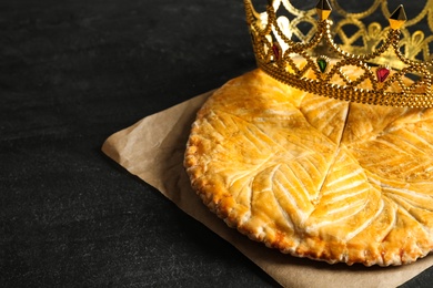 Photo of Traditional galette des Rois with decorative crown on black table