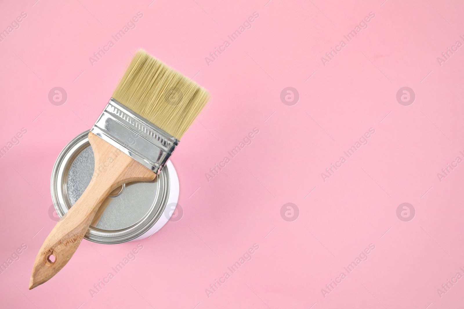 Photo of Closed can of paint with brush on color background, top view. Space for text