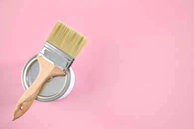 Photo of Closed can of paint with brush on color background, top view. Space for text