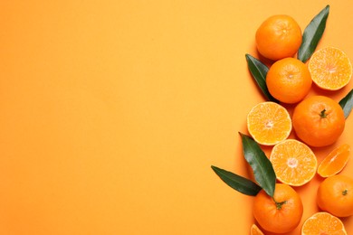 Photo of Flat lay composition with fresh ripe tangerines and space for text on orange background. Citrus fruit