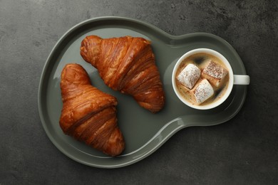 Photo of Tasty croissants served with cup of hot drink on grey textured table, top view