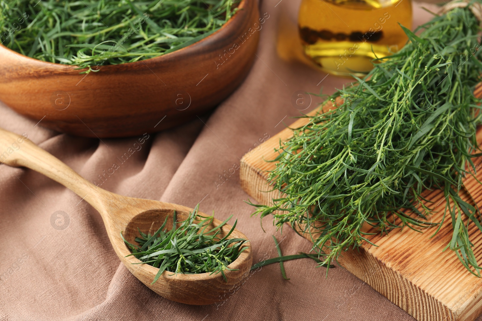 Photo of Fresh green tarragon sprigs on pink tablecloth