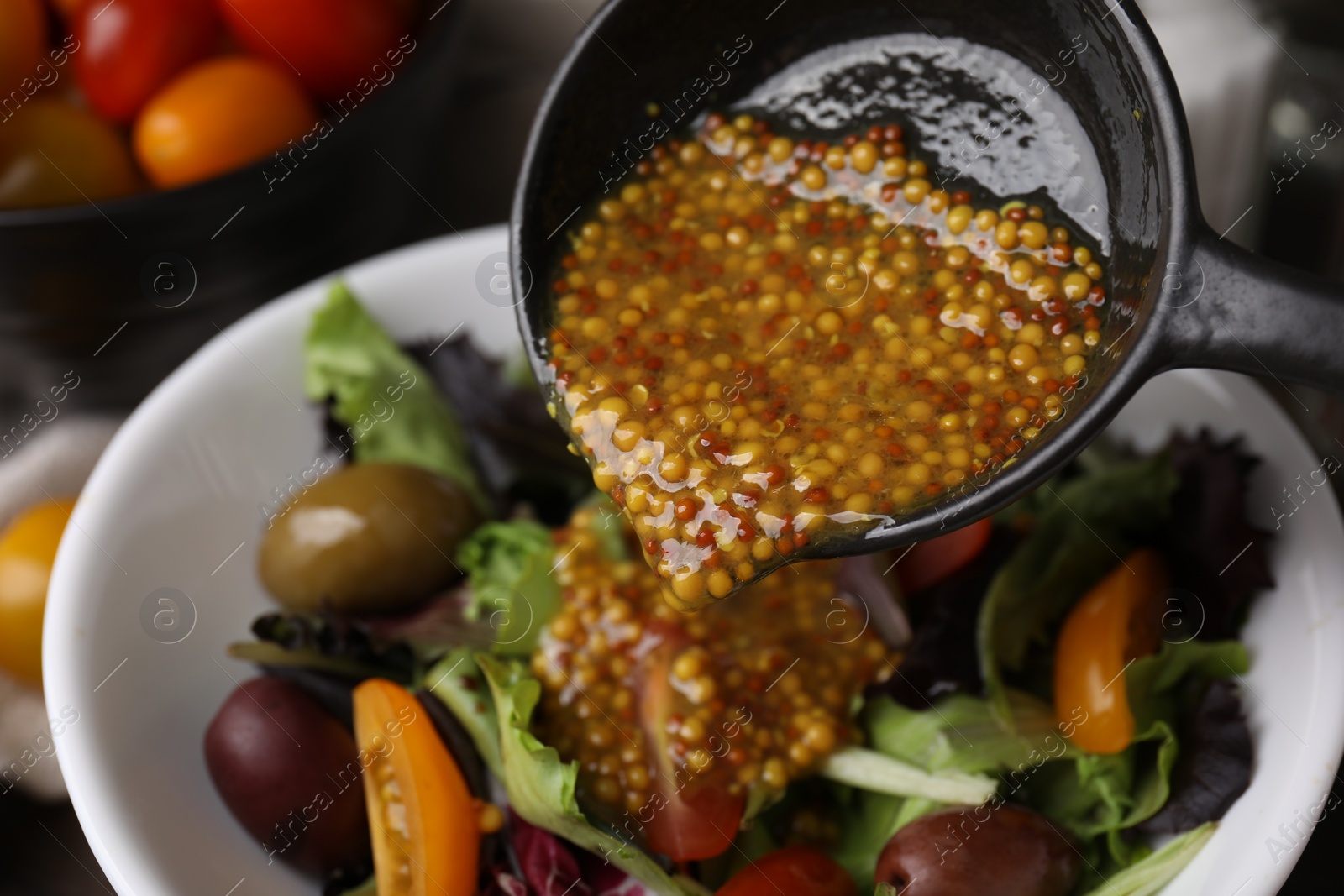 Photo of Pouring tasty vinegar based sauce (Vinaigrette) into bowl with salad, closeup