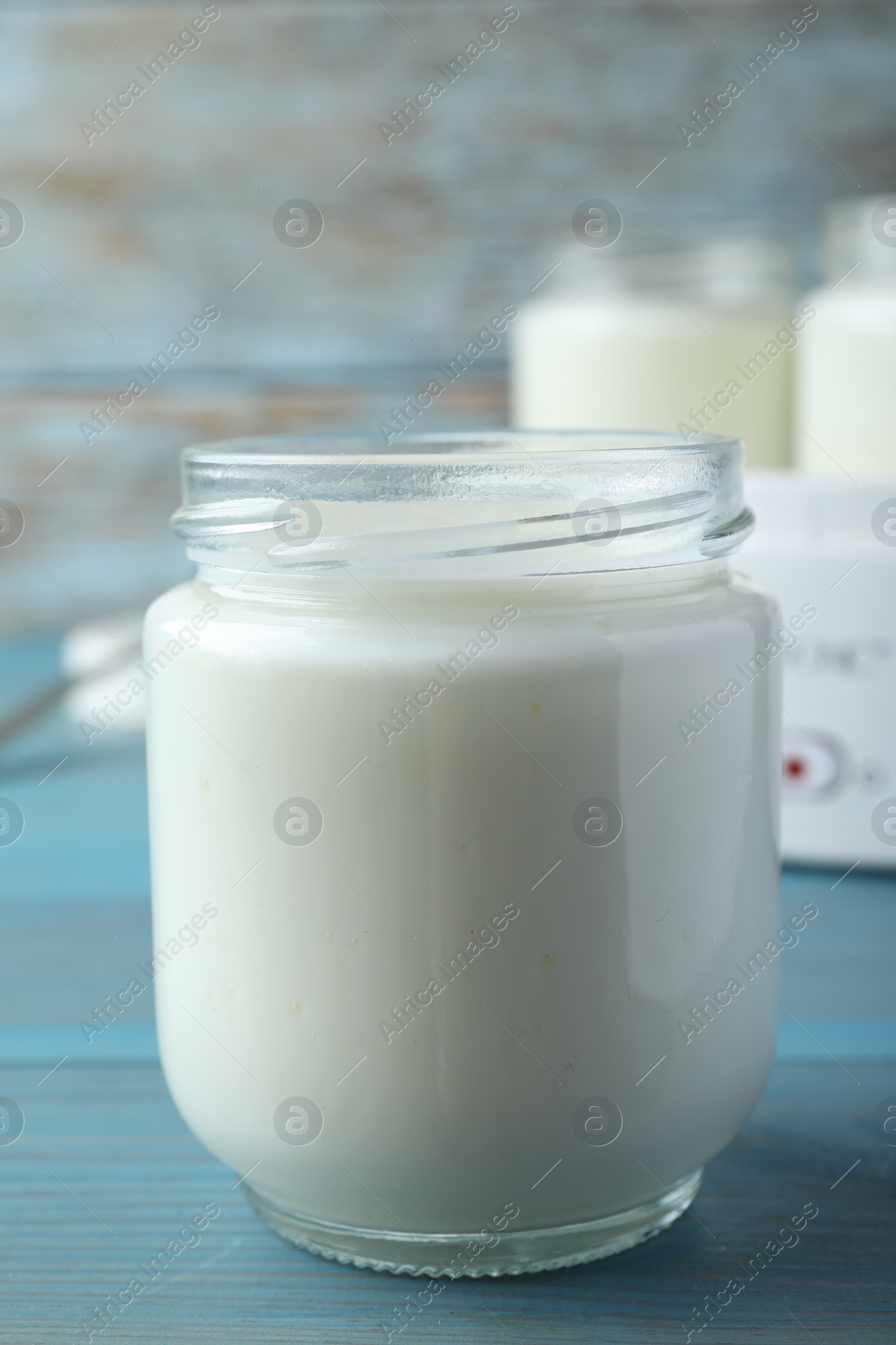 Photo of Glass jar with tasty yogurt on blue wooden table