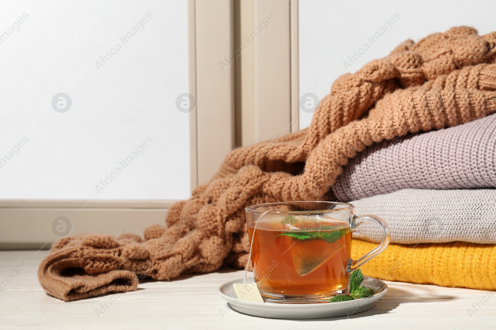 Photo of Cup of fresh tea on windowsill indoors, space for text. Winter drink