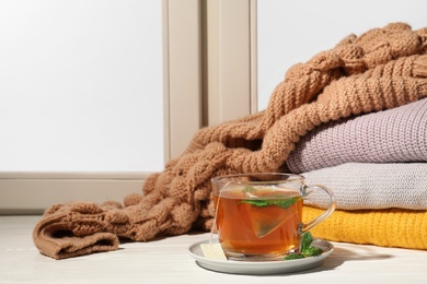 Photo of Cup of fresh tea on windowsill indoors, space for text. Winter drink