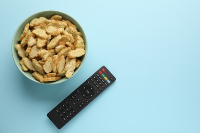 Photo of Remote control and rusks on light blue background, flat lay. Space for text