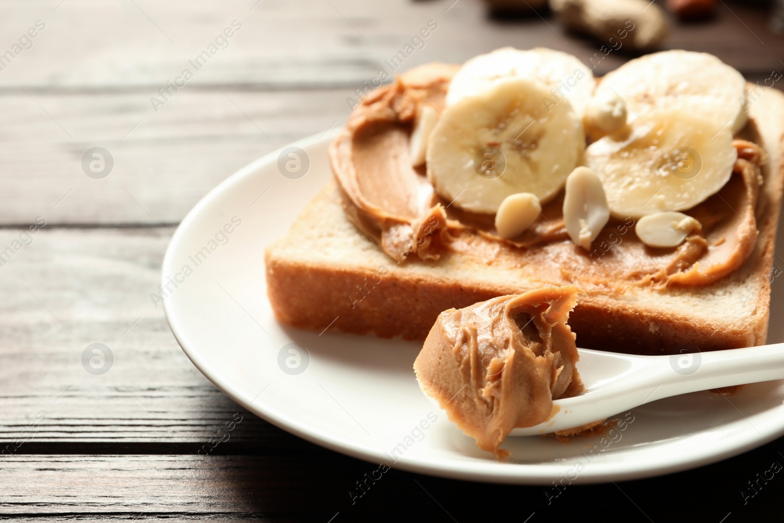Photo of Toast bread with peanut butter and banana slices on wooden table, closeup