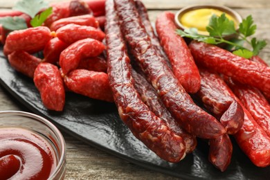 Thin dry smoked sausages served on wooden table, closeup