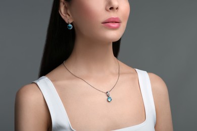 Young woman with elegant jewelry on dark grey background, closeup