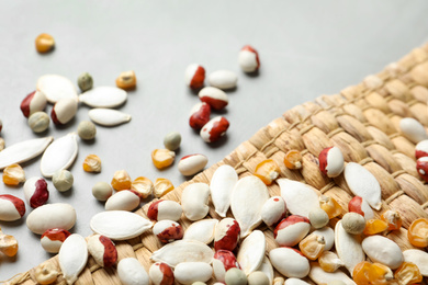 Mixed vegetable seeds and wicker mat on grey background, closeup