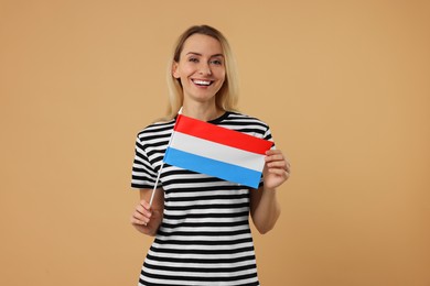 Photo of Happy woman with flag of Netherlands on beige background