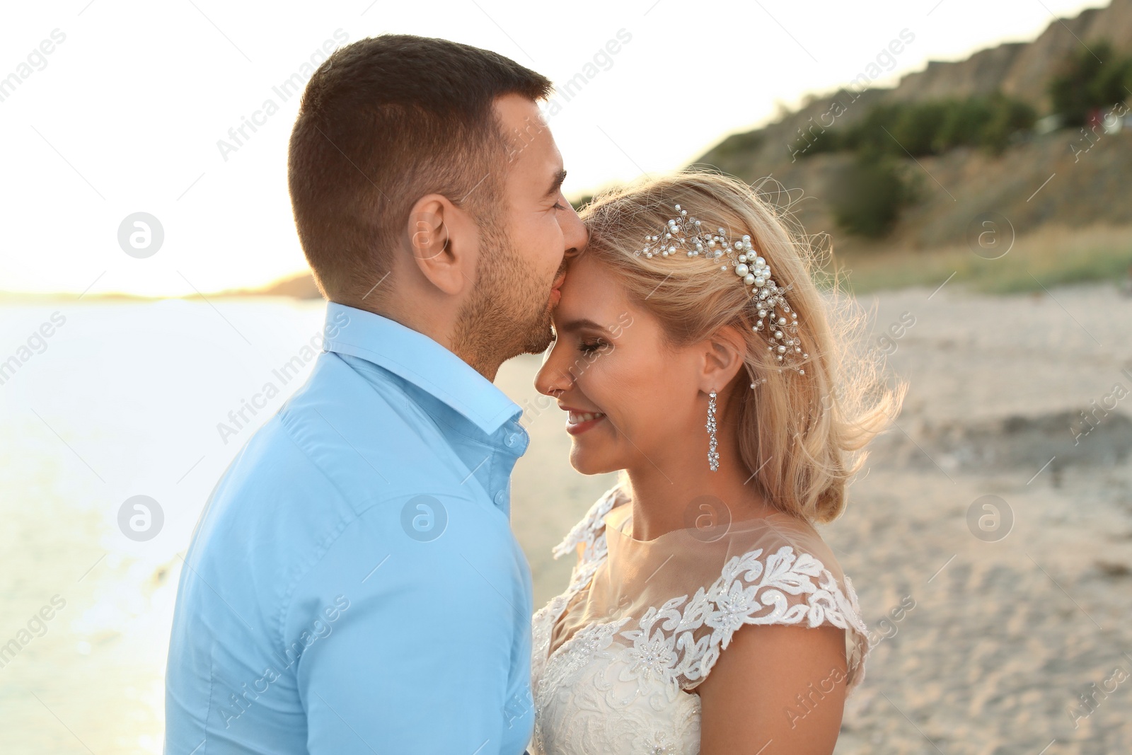 Photo of Wedding couple. Groom kissing bride on beach