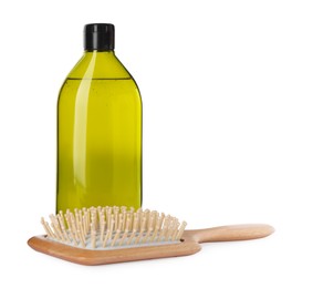 Bottle of shampoo and wooden brush on white background