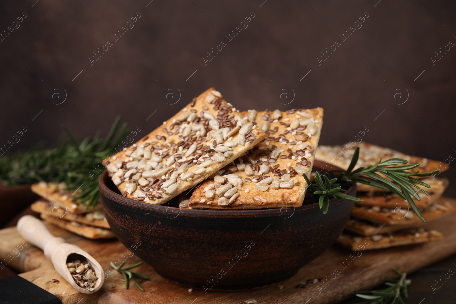 Photo of Cereal crackers with flax, sunflower, sesame seeds and rosemary on table, closeup