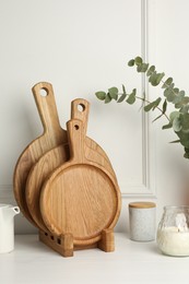 Photo of Wooden cutting boards, teapot, candle and eucalyptus branches on white table