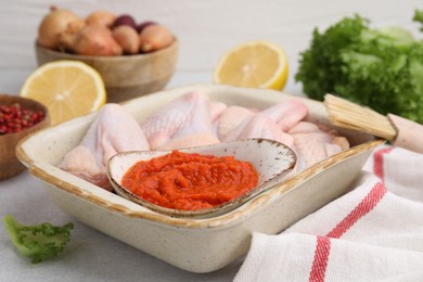 Photo of Fresh marinade, raw chicken and other products on light table, closeup